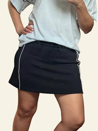 Person wearing a white shirt and black skirt with cream background