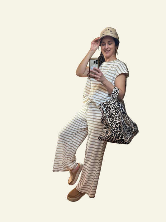 Woman in striped outfit with leopard print bag on a white background