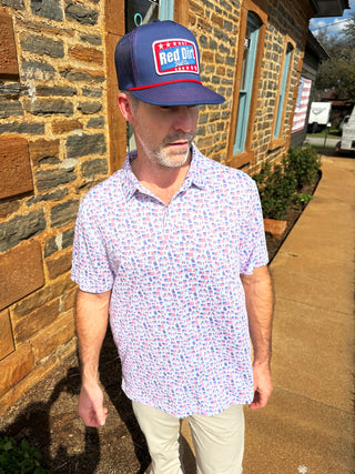 Man wearing a patterned shirt and cap on a stone patio
