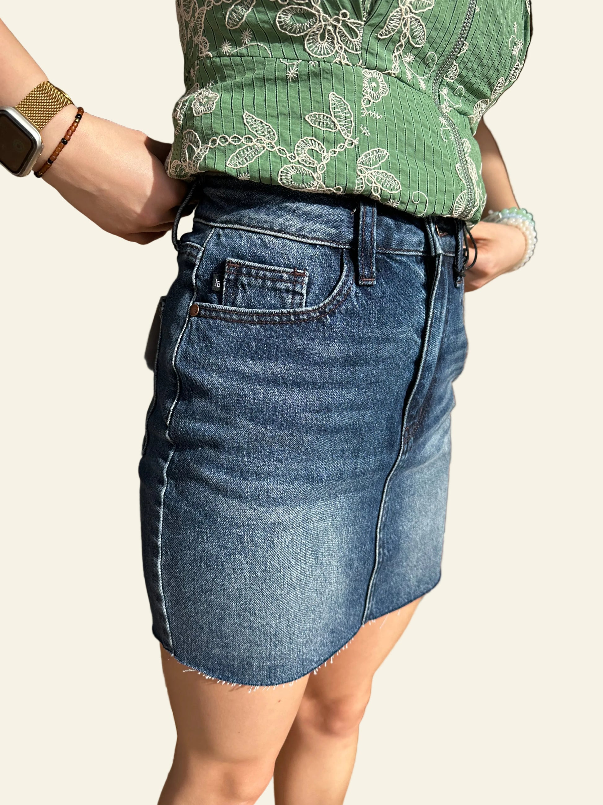 Person wearing a green top and blue denim shorts sitting on a stone floor.