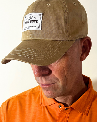 Man wearing a brown cap and orange shirt with a visible brand logo.