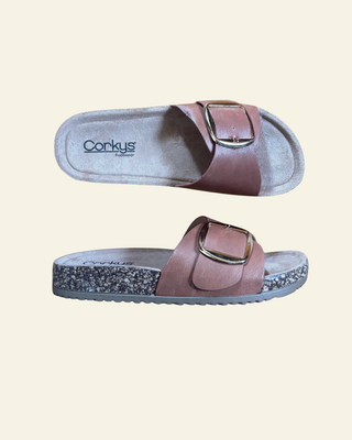 Pair of cork sandals with a buckle on a beige background