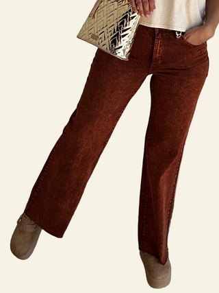 A person standing in an upright position wearing high-waisted, garment-dyed, raw hem retro style Pumpkin Spice wide leg pants in a brown color.