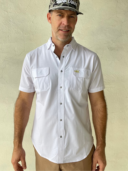 Man wearing a white shirt and camouflage cap against a beige wall