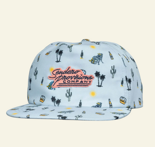 A blue baseball cap with patterned designs including what appears to be cacti, animals, and text related to the brand 'Sendero Provisions Co.'.