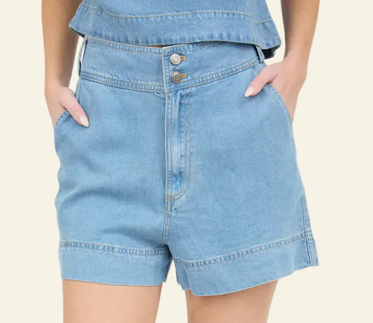 A pair of high-waisted blue chambray mini shorts with a double button and zipper closure, and belt loops.