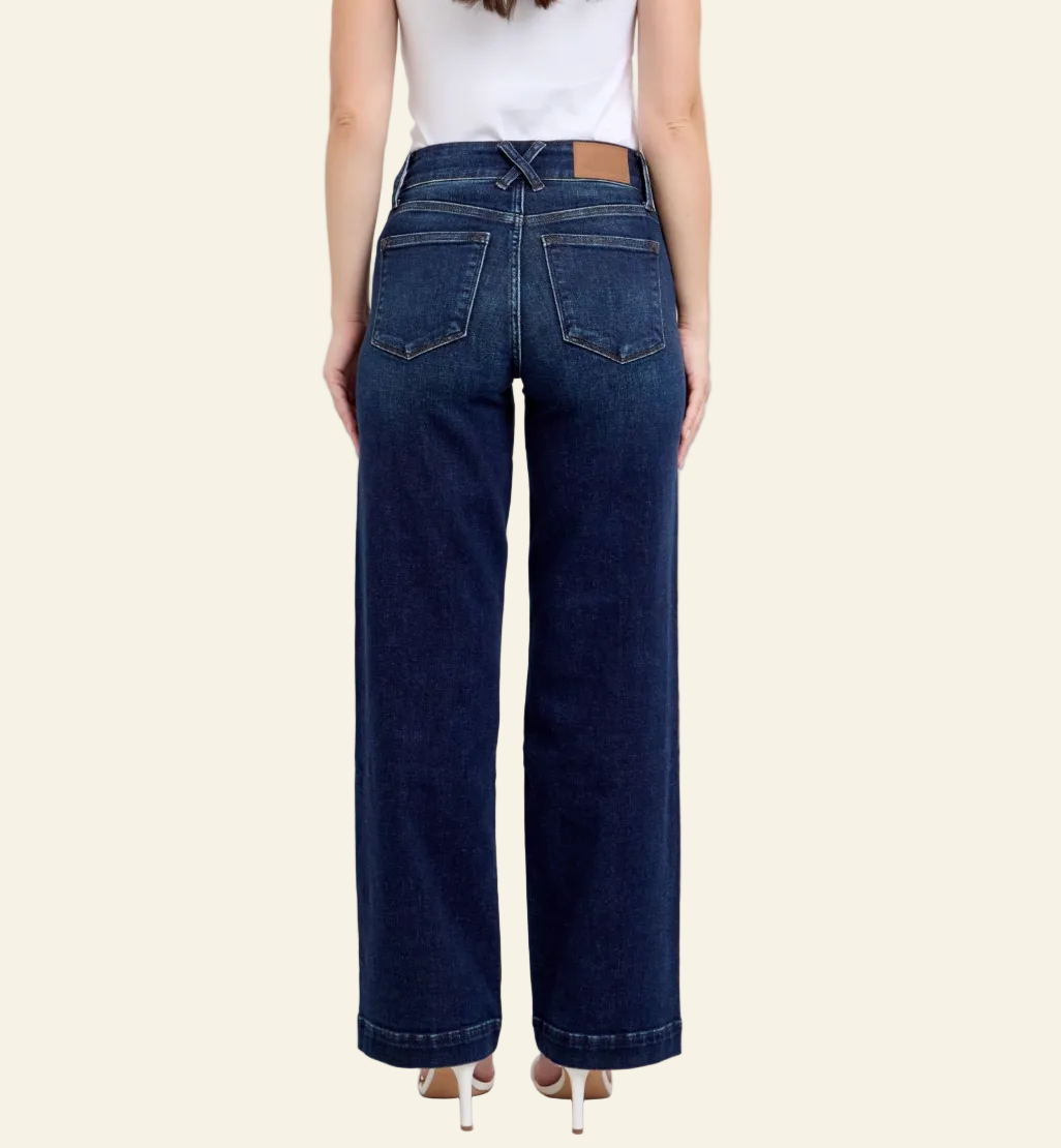 Person wearing dark blue jeans on a plain background