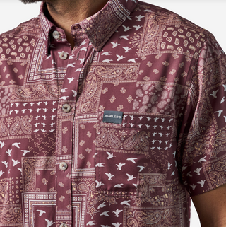 Close-up of a maroon patterned shirt with a brand label on a white background