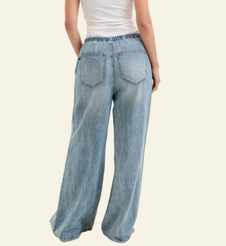 Person wearing light blue wide-leg jeans on a plain background