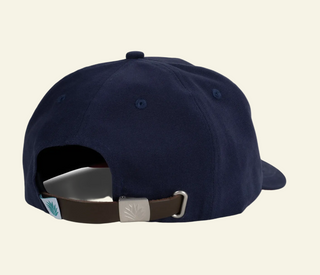 Navy blue baseball cap with a brown strap on a beige background