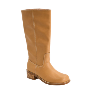 A tall tan leather boot with a low stacked heel and contrast stitching, shown from a three-quarters angle on a light tan background.