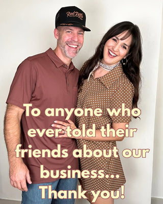 A smiling man in a maroon polo shirt and blue jeans stands next to a woman in a brown polka-dot dress, both wearing Red Dirt branded hat, with a large text overlay thanking anyone who referred their friends to our business.